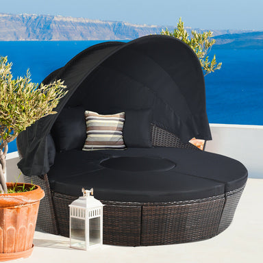 Black Rattan Round Daybed with Retractable Canopy, Adjustable Table & 3-Piece Seating Arrangement for outdoor relaxation with scenic ocean view.