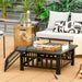 32-Inch 3-In-1 Outdoor Square Fire Pit Table with BBQ Grill, Ice Bucket & Rain Cover set up for outdoor cooking, featuring grilled meat and vegetables, surrounded by stylish outdoor seating.