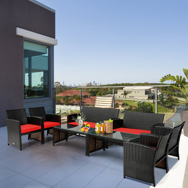 4 Piece Rattan Outdoor Cushion Furniture Set with Red Cushions & Glass Table for Relaxation, beautifully arranged on a modern patio with a scenic view.