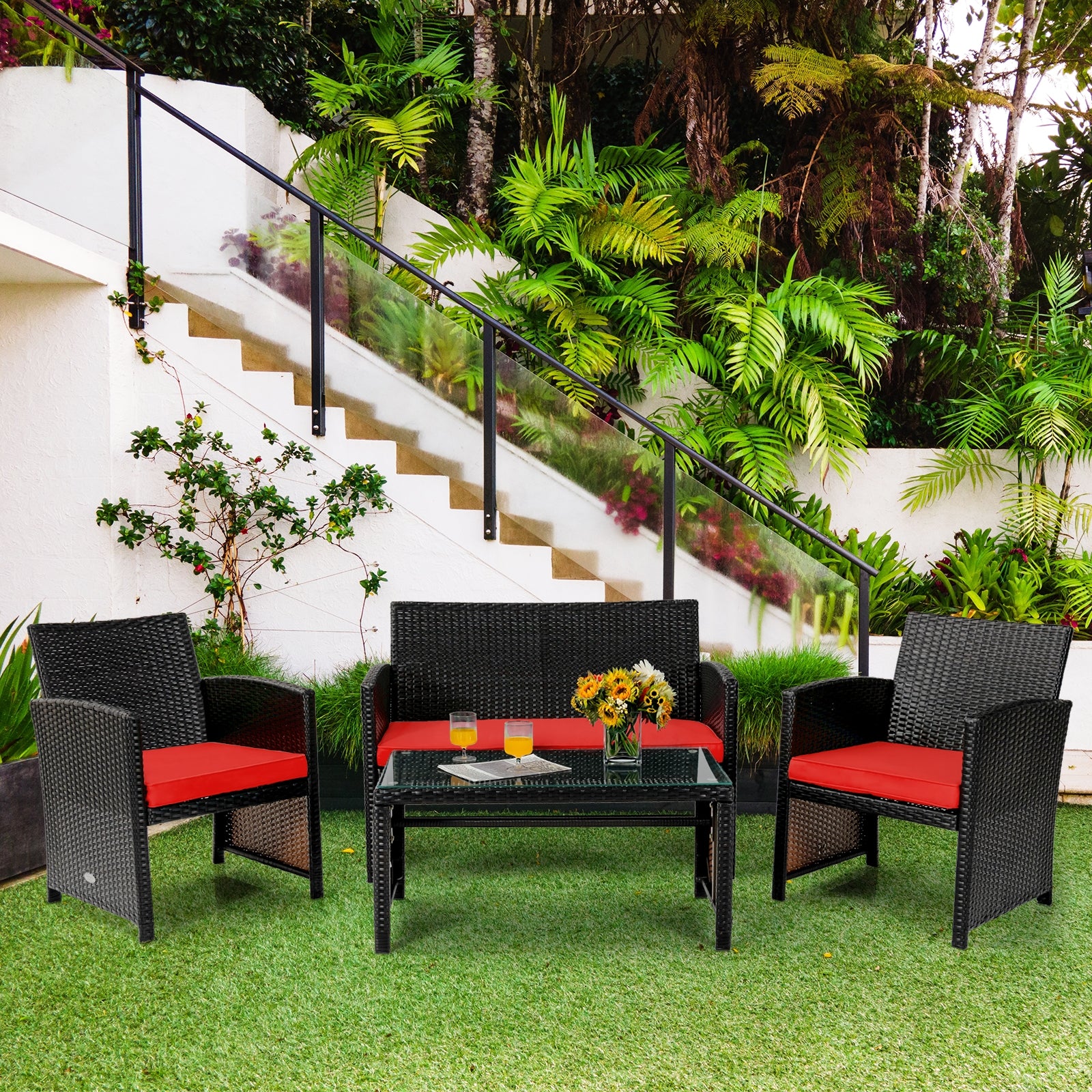 4 Piece Rattan Outdoor Cushion Furniture Set with Red Cushions arranged beautifully in a lush garden environment, ideal for gatherings.
