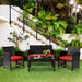4 Piece Rattan Outdoor Cushion Furniture Set with Red Cushions arranged beautifully in a lush garden environment, ideal for gatherings.