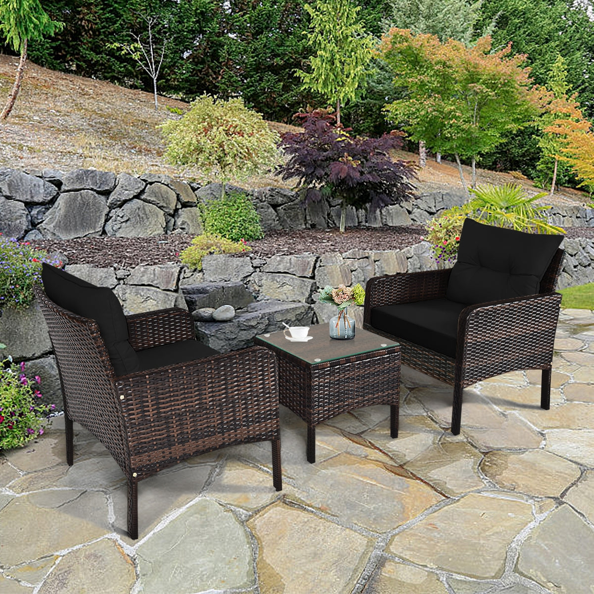 3-Piece Black Rattan Outdoor Patio Conversation Set with Cushions & Glass Table displayed in a beautiful garden setting, perfect for relaxation and socializing.
