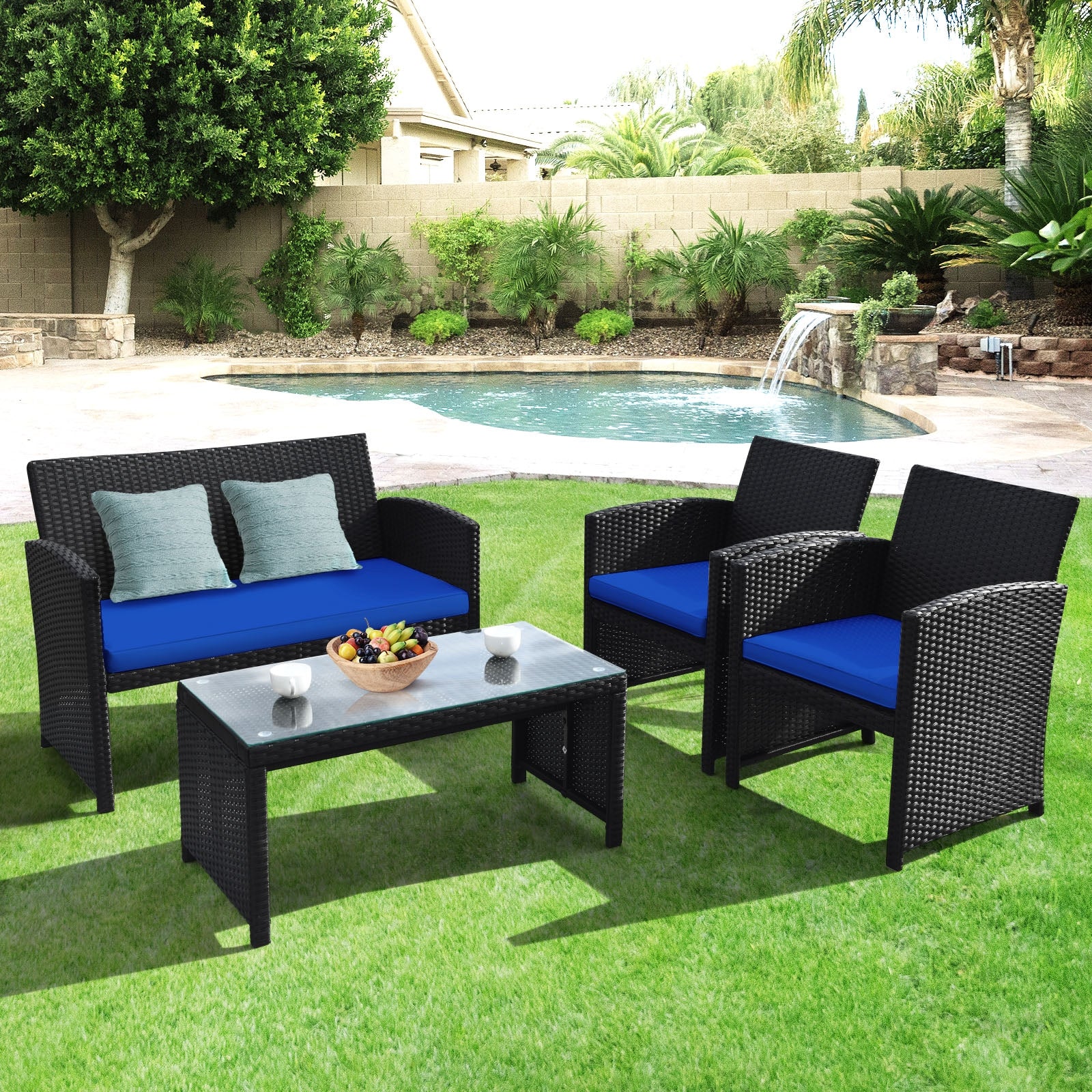 4-Piece Navy Rattan Patio Furniture Set with Weather-Resistant Cushions & Tempered Glass Table in a backyard setting, featuring two armchairs and a loveseat with blue cushions.