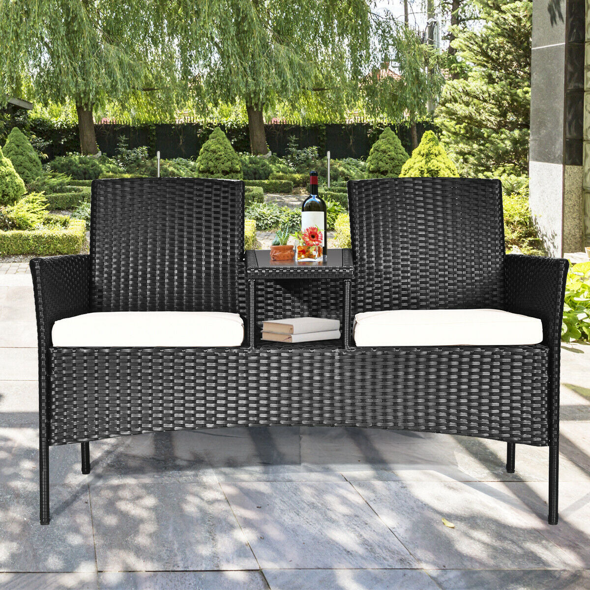 Dream Yard Oasis Wicker Patio Conversation Set placed in a garden setting, featuring decorative items on the table and a stylish design suitable for outdoor spaces.