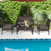 4-Piece Patio Rattan Furniture Set with Cushions, Loveseat, & Table - Brown Outdoor Bliss arranged by a pool, with decor items on the coffee table and vibrant greenery around.