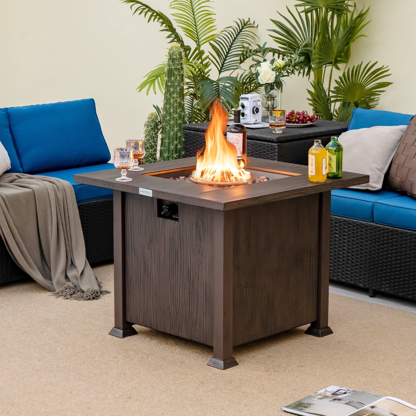 The 32 Inch Square Fire Pit Table with flames, set in a stylish outdoor living area, demonstrating its dual functionality as a fire pit and coffee table.