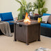 The 32 Inch Square Fire Pit Table with flames, set in a stylish outdoor living area, demonstrating its dual functionality as a fire pit and coffee table.
