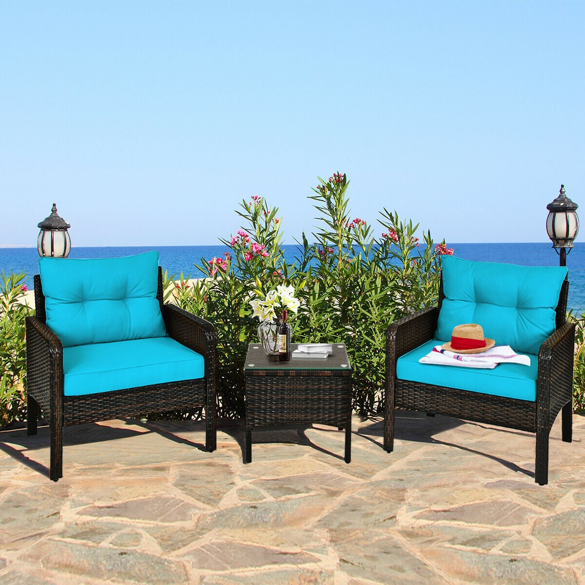 3-Piece Turquoise Outdoor Rattan Conversation Set with Cushions in a picturesque outdoor setting by the sea, featuring vibrant turquoise cushions on stylish rattan chairs and a matching table.