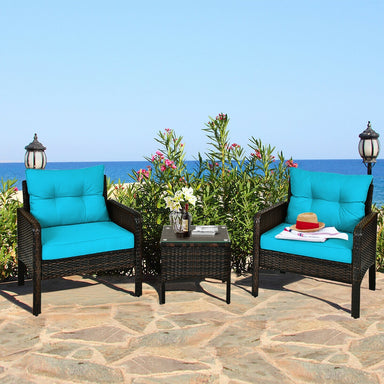 3-Piece Turquoise Outdoor Rattan Conversation Set with Cushions in a picturesque outdoor setting by the sea, featuring vibrant turquoise cushions on stylish rattan chairs and a matching table.