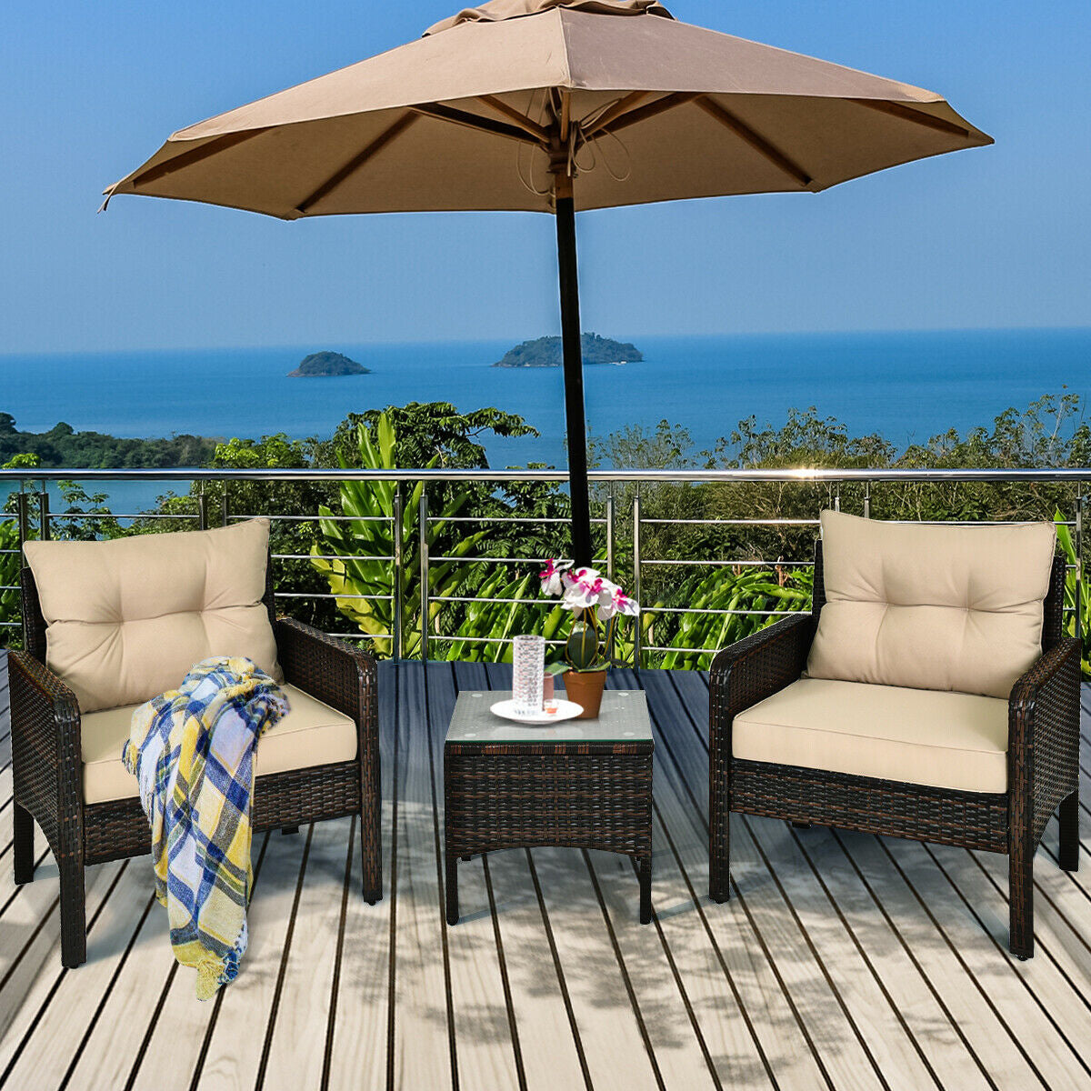 Stylish setup of the 3-Piece Beige Rattan Outdoor Patio Conversation Set with cushions, table, and an umbrella overlooking a scenic view.