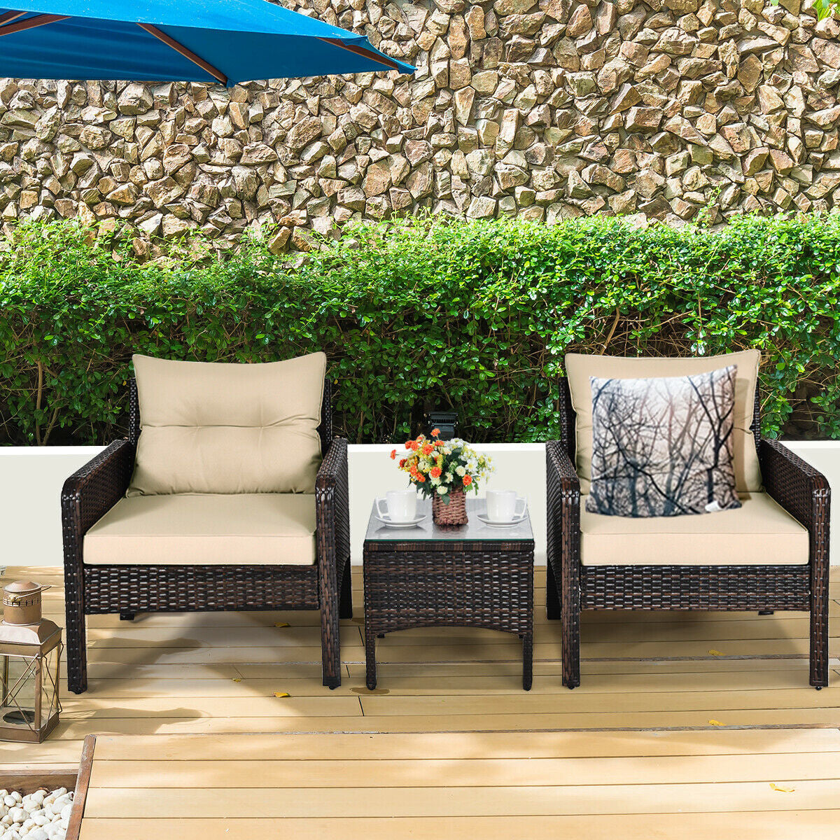 3-Piece Beige Rattan Outdoor Patio Conversation Set with Cushions & Tempered Glass Table set against a stone wall and greenery, perfect for outdoor relaxation.