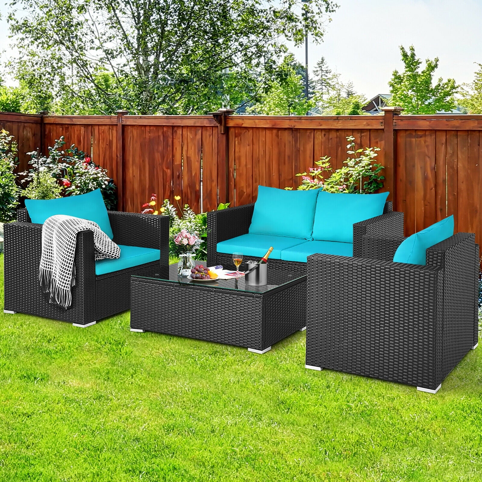 4-Piece Turquoise Patio Rattan Sofa Set with Cushions & Tempered Glass Table in a vibrant outdoor setting with green grass and a wooden fence.