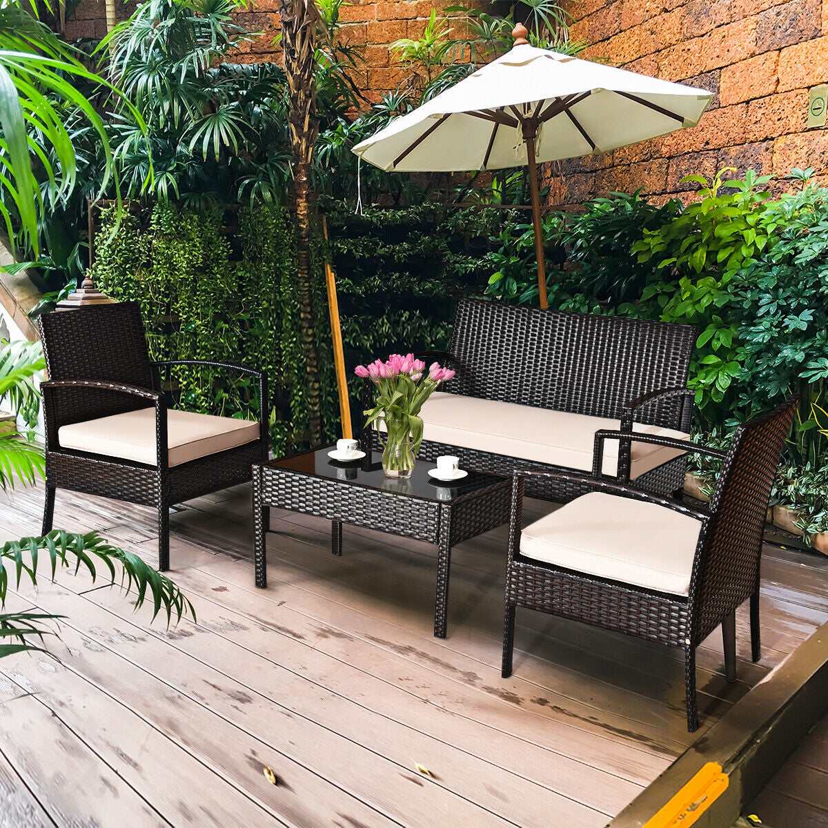 4-Piece Outdoor Patio Rattan Conversation Set with Loveseat, 2 Single Sofas & Glass Table set in a lush garden, showcasing the stylish design with cream cushions.