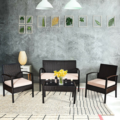 4-Piece Outdoor Patio Rattan Conversation Set with Loveseat, 2 Single Sofas & Glass Table arranged in a stylish indoor setting, featuring cushions and decorative items.