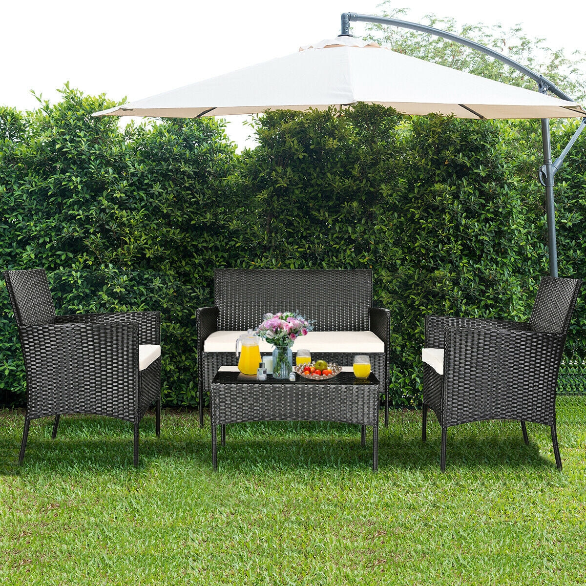 4-Pc Outdoor Patio Rattan Sofa Set with Cushions showcased in a green garden, featuring a stylish white loveseat, two single chairs, and a glass coffee table perfect for outdoor gatherings.