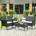4-Pc Outdoor Patio Rattan Sofa Set with Cushions set in a lush garden, showcasing the black rattan chairs and table with decorative elements.