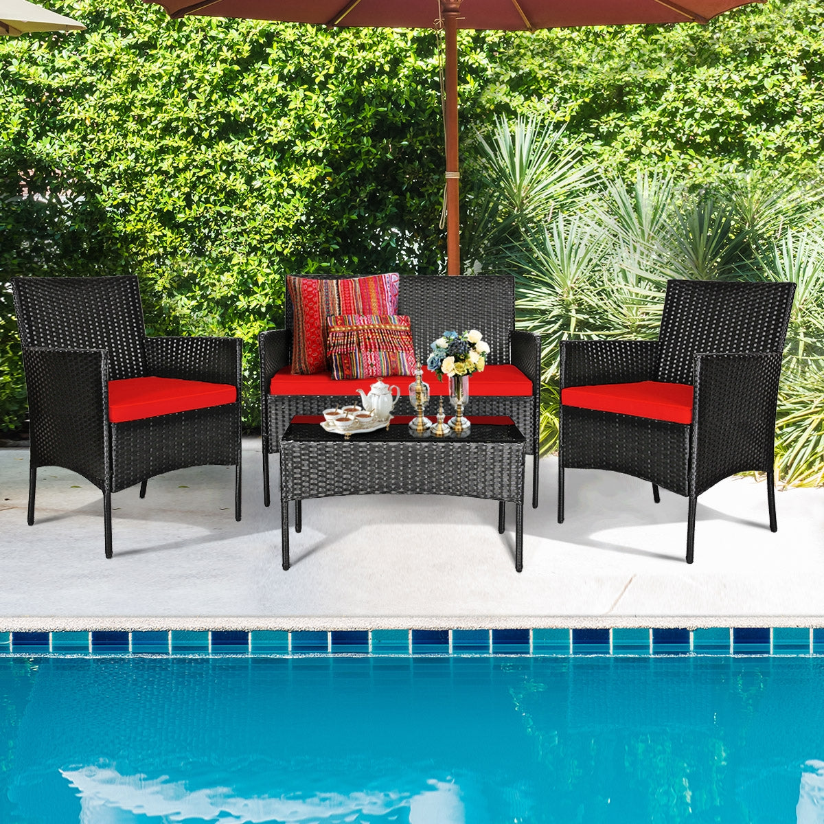 4 Piece Red Patio Rattan Sofa Set with Cushions & Glass Table featuring two single chairs and a loveseat around a glass-top coffee table by the pool. Ideal for outdoor relaxation.