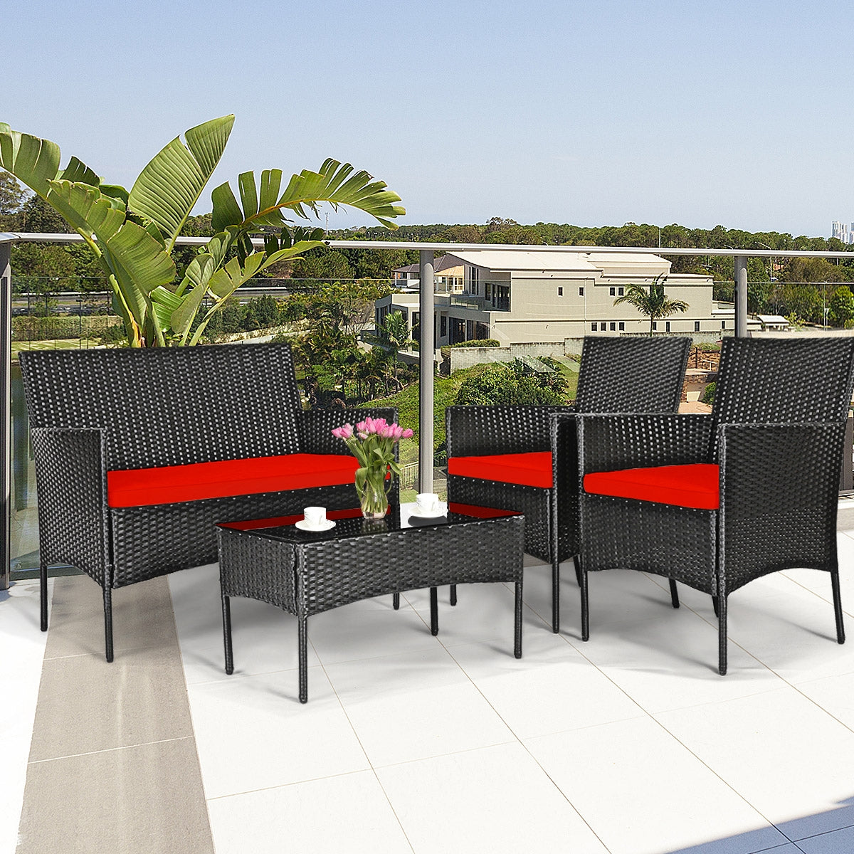 4 Piece Red Patio Rattan Sofa Set with Cushions & Glass Table set on a modern balcony with a view, showcasing stylish rattan chairs and a loveseat, great for outdoor gatherings.