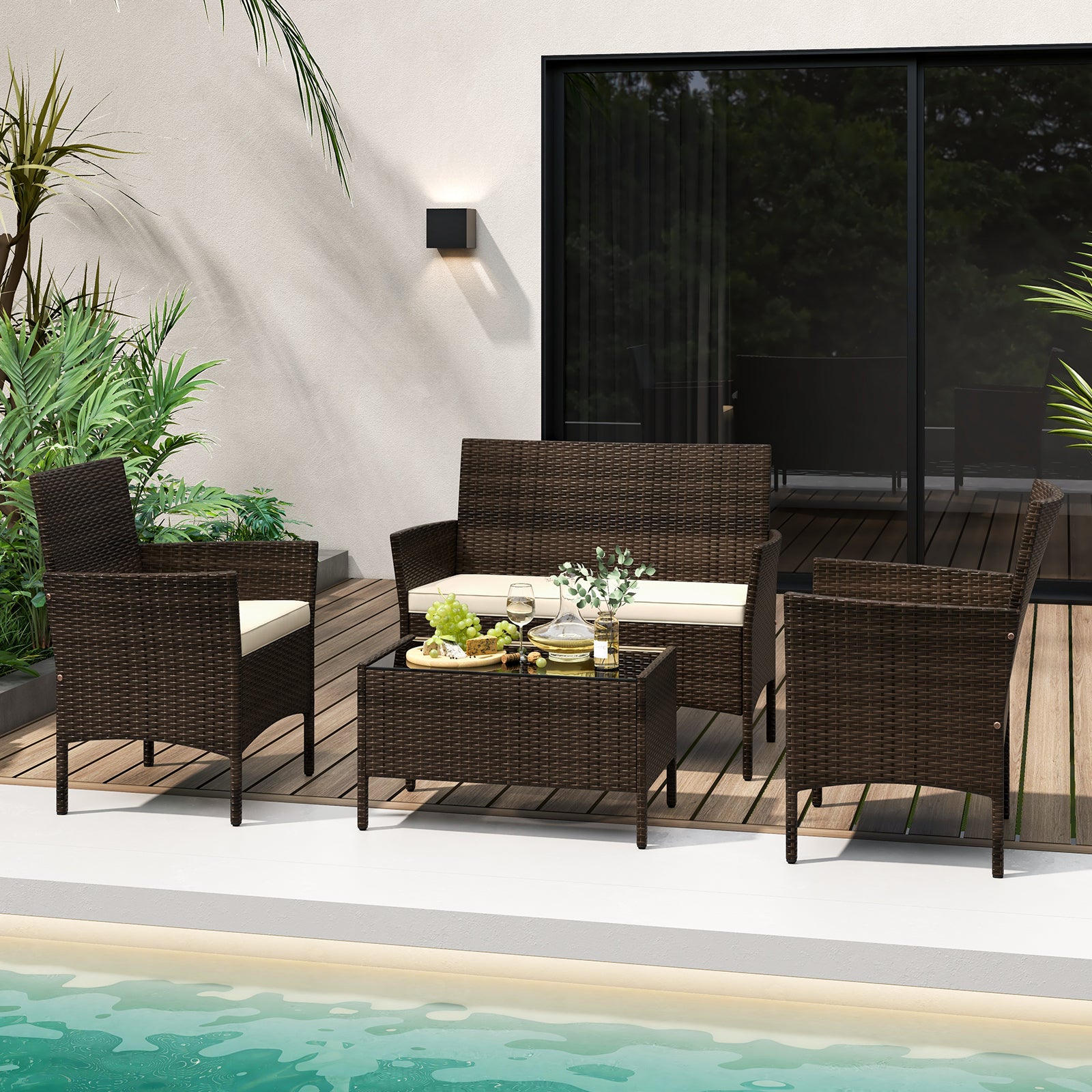 4-Piece Beige Patio Rattan Conversation Set with Cushions, Glass Table & Ergonomic Design displayed in an outdoor setting with plants and a pool.