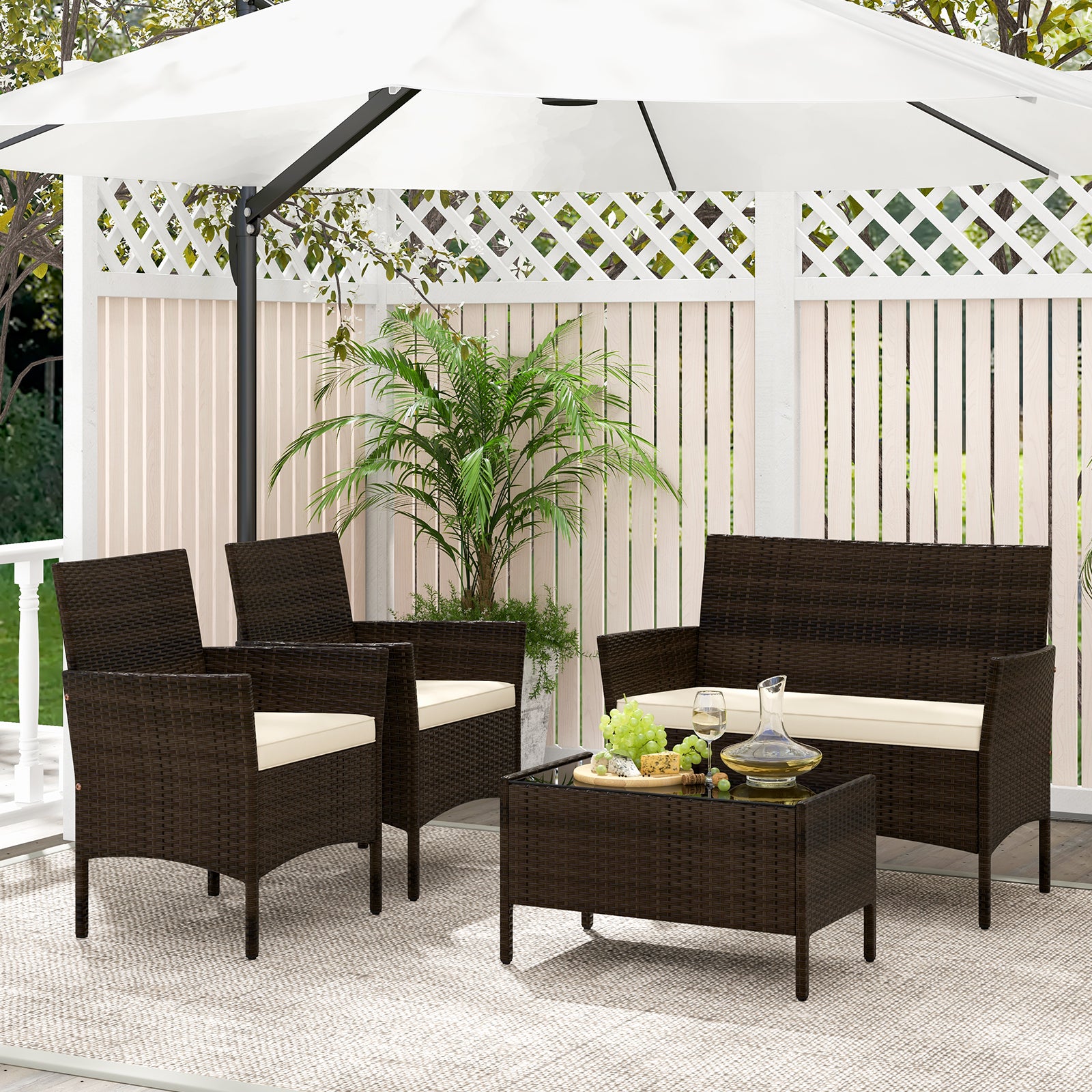 4-Piece Beige Patio Rattan Conversation Set with Cushions, Glass Table & Ergonomic Design displayed in a stylish outdoor setting with umbrella and greenery.