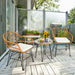 Stylish balcony view with the 3-Piece White Rattan Furniture Set with Cushioned Chairs and Glass Top Table for Outdoor Relaxation, highlighting two comfortable rattan chairs, a round table, and a decorative arrangement with sunflowers.
