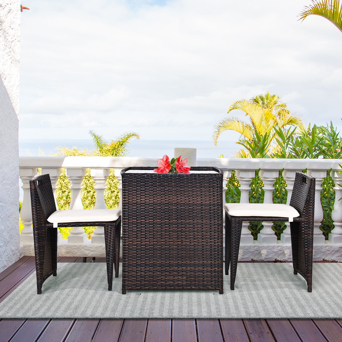 3-Piece Outdoor Wicker Patio Set with Cushions, No Assembly, Space-Saving Glass Table showcased on a balcony with a scenic view, featuring two foldable chairs and a stylish glass-top table adorned with a decorative plant.