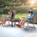 People relaxing in Dream Yard Oasis Folding Recliner Lounge Chairs with Canopy, enjoying the outdoor setting with a cup holder and adjustable features.