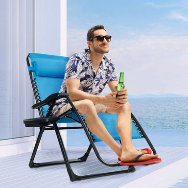 A stylish man sitting in an oversized heavy duty lounge chair with adjustable backrest and cup holder by Dream Yard Oasis™, holding a drink while enjoying the sea view.