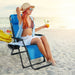 A young woman enjoying a sunny day at the beach while sitting in the Dream Yard Oasis oversized heavy-duty lounge chair with adjustable backrest and cup holder - blue - 500 lbs capacity.