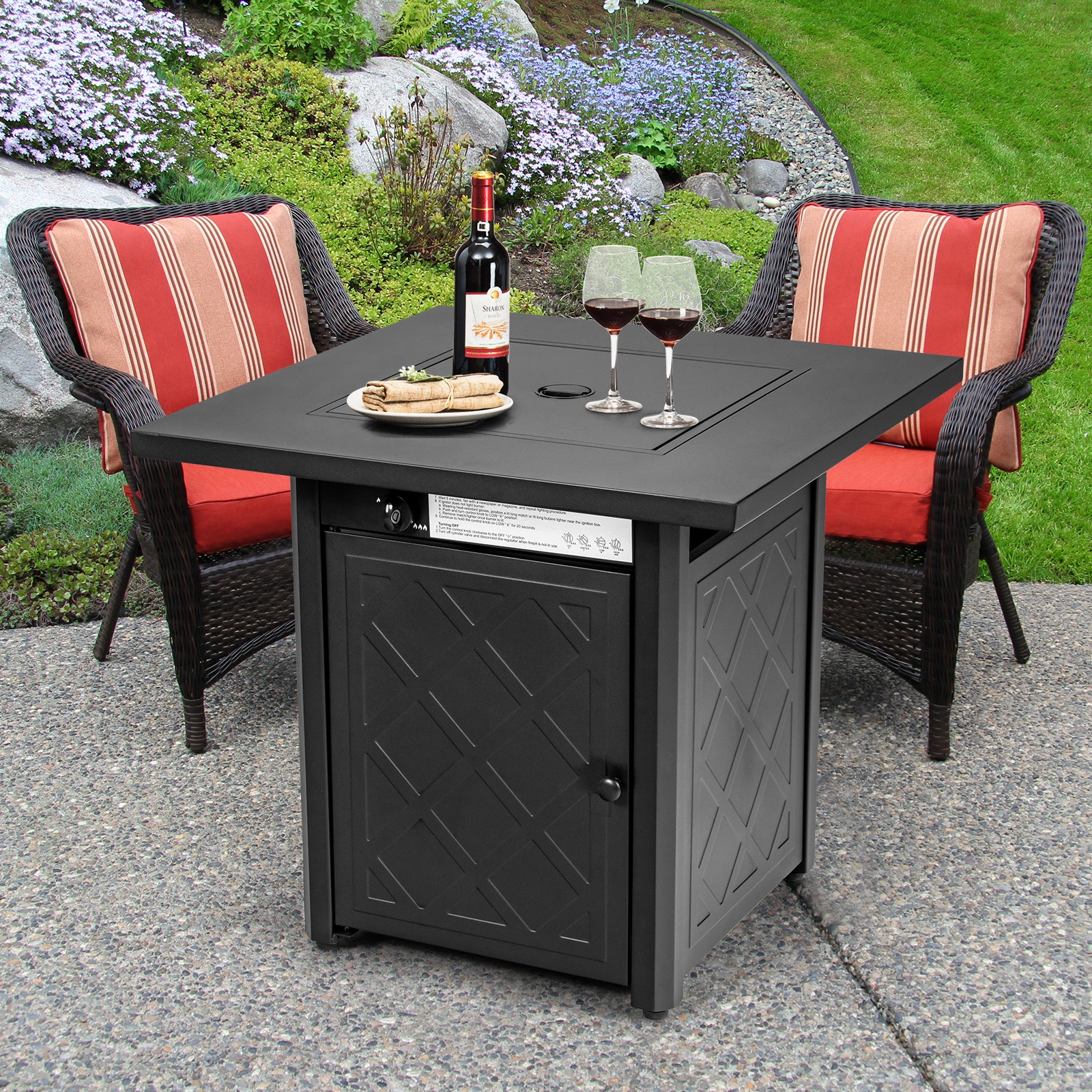 28 Inch Propane Gas Fireplace with Lava Rock - Black, featuring a stylish patio square design, accompanied by red striped chairs, wine glasses, and a bottle in an outdoor setting.