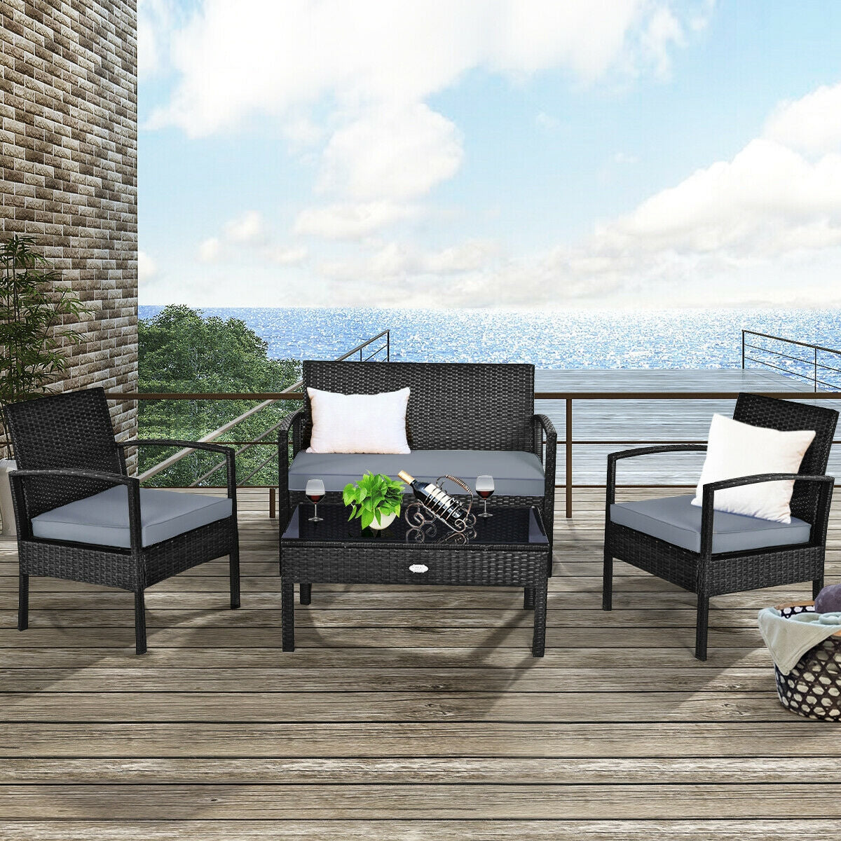 4-Piece Black Patio Rattan Furniture Set with Loveseat, Coffee Table & Cushions placed on a stylish outdoor deck with a view of the ocean, featuring soft gray cushions and decorative pillows.