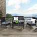 4-Piece Black Patio Rattan Furniture Set with Loveseat, Coffee Table & Cushions placed on a stylish outdoor deck with a view of the ocean, featuring soft gray cushions and decorative pillows.