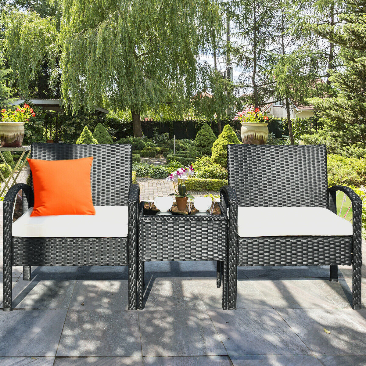 The 3 Piece Outdoor Rattan Sofa Set with Cushions and Glass Table for Patio and Garden, beautifully arranged in a serene outdoor setting with greenery.