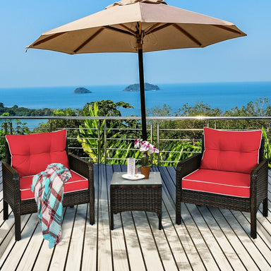 3-Piece Outdoor Patio Rattan Conversation Set with Red Cushions, featuring two comfortable chairs under an umbrella with a scenic ocean view.