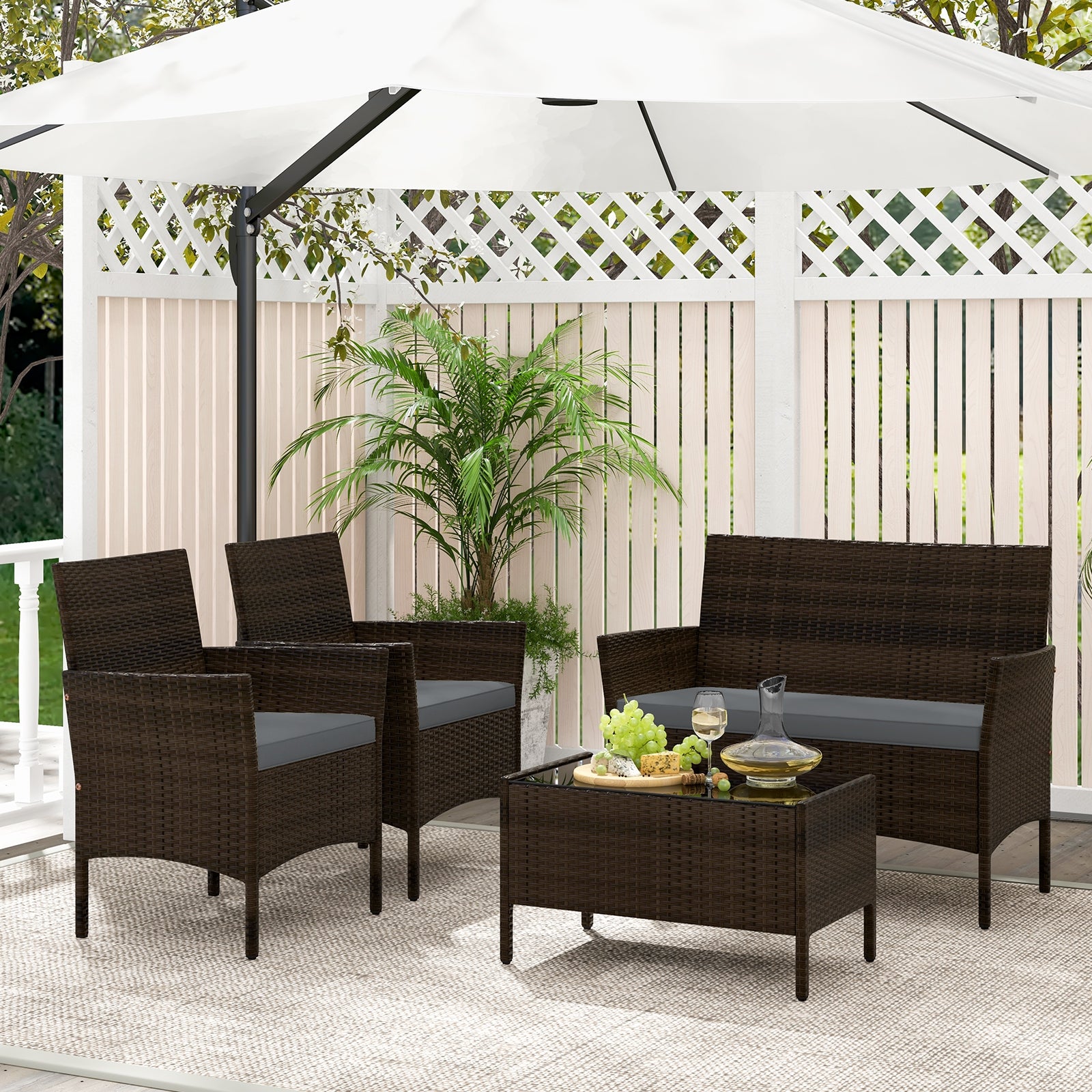 4-Piece Gray Patio Rattan Conversation Set with Comfortable Cushions & Sturdy Design, arranged under a stylish umbrella with decorative plants in a cozy outdoor space.