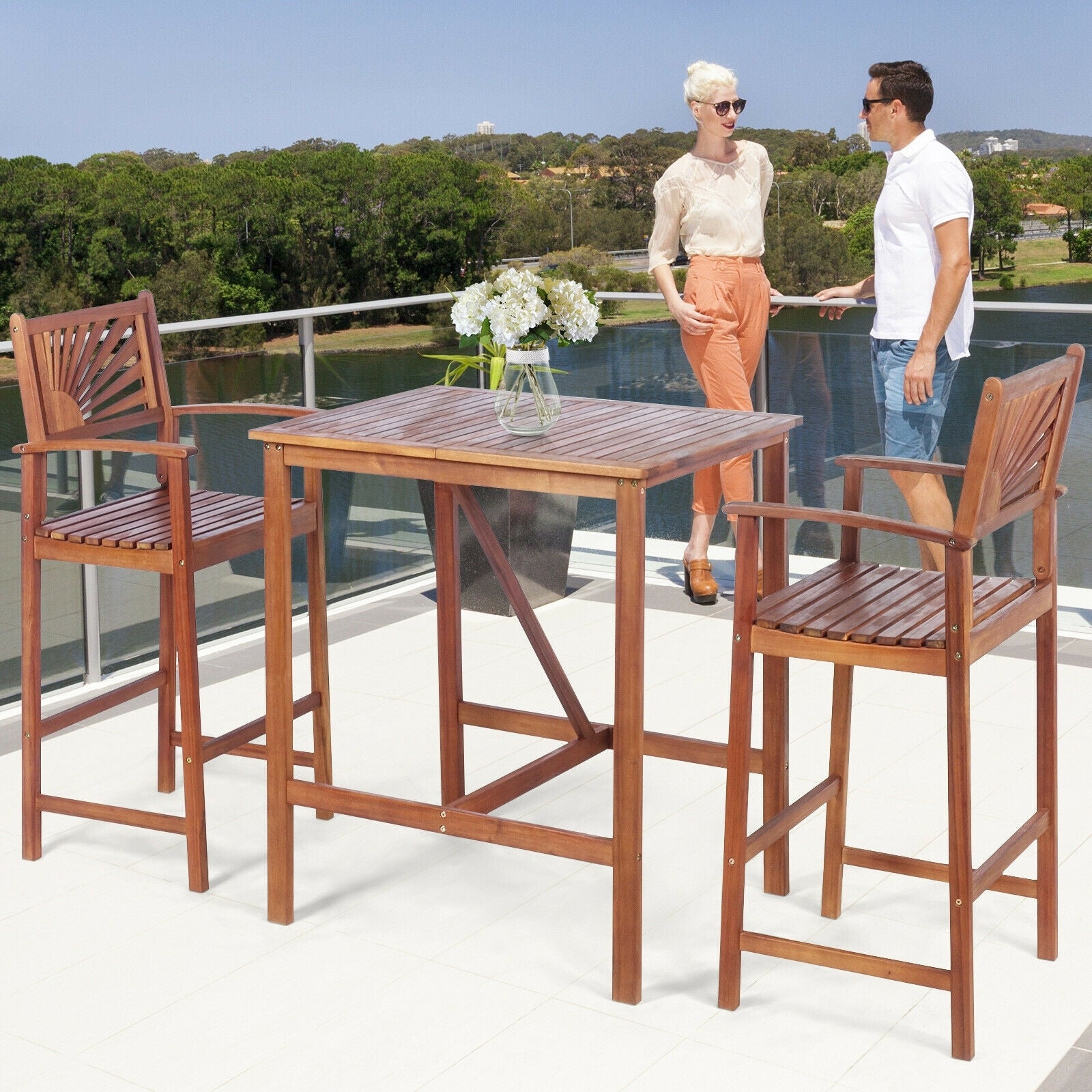Two people enjoying the 3-Piece Acacia Wood Patio Bar Set with Sunflower Backrest on a scenic balcony, showcasing its stylish and functional design.