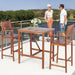 Two people enjoying the 3-Piece Acacia Wood Patio Bar Set with Sunflower Backrest on a scenic balcony, showcasing its stylish and functional design.